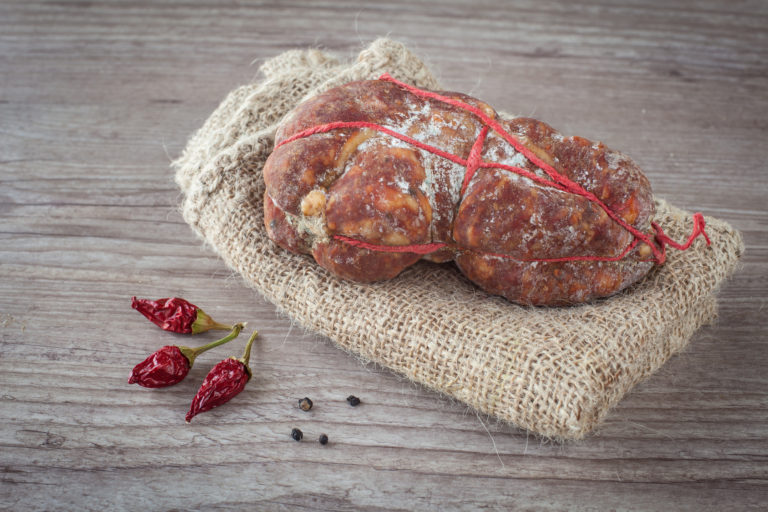 Tasty italian Soppressata ham on wooden background